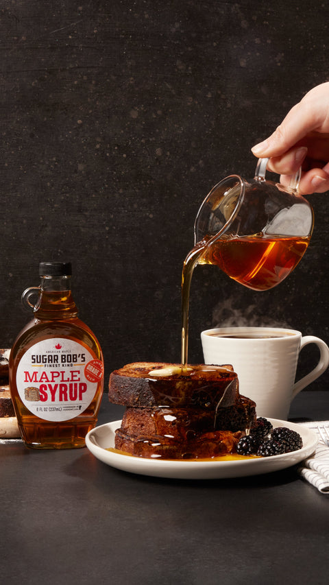 Sugar Bob's Maple Syrup bottle with syrup being poured over French toast, served with blackberries and coffee