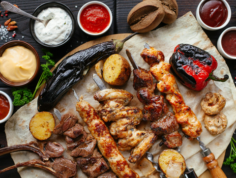 Grill filled with BBQ ribs, veggies, and glazed meats using Sugar Bob’s smoked maple and sriracha sauces
