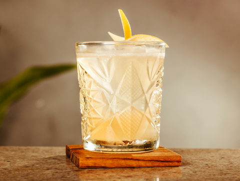 Maple cider cocktail garnished with cinnamon stick and a drizzle of smoked maple syrup