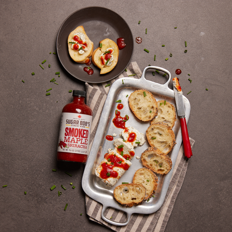 A bottle of Sugar Bob’s Habanero Mapple Sriracha next to a bowl of Mexican street corn