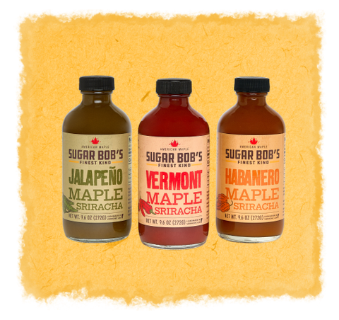 Three bottles of Sugar Bob's Maple Sriracha on a textured yellow background