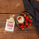 Maple sugar package with strawberries and a bowl of sugar on a wooden table.