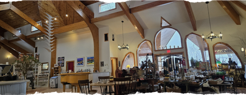 Panoramic view of a cozy restaurant interior with wooden beams and large windows.