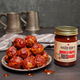 Plate of meatballs and a jar of Smoked Maple BBQ Sauce on a dark surface.